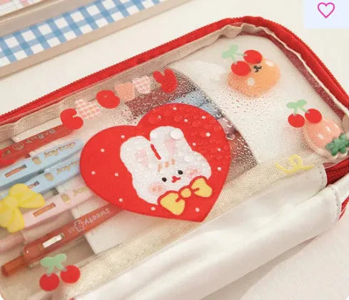 Transparent heart-shaped TPU pencil case in a pink multicolour Korean-style design with cake and rabbit motifs.