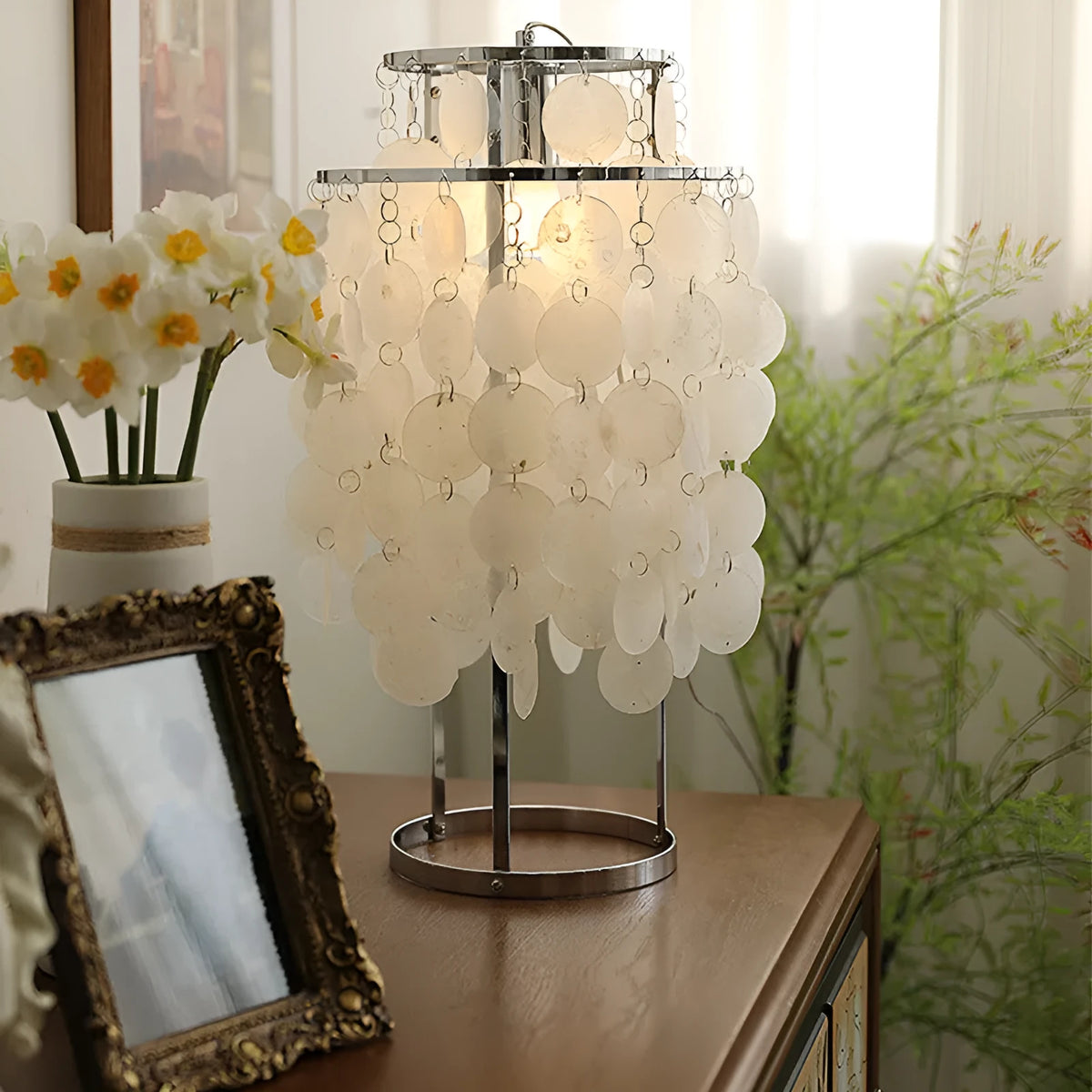 Modern single-head Shell bedside table lamp in chrome finish on a wooden table.