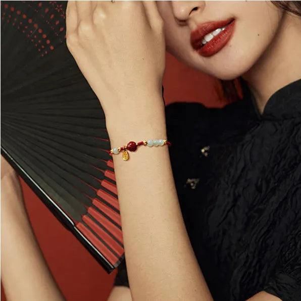 Women's adjustable silver bracelet with Hetian jade and red cinnabar rope decoration on a light background