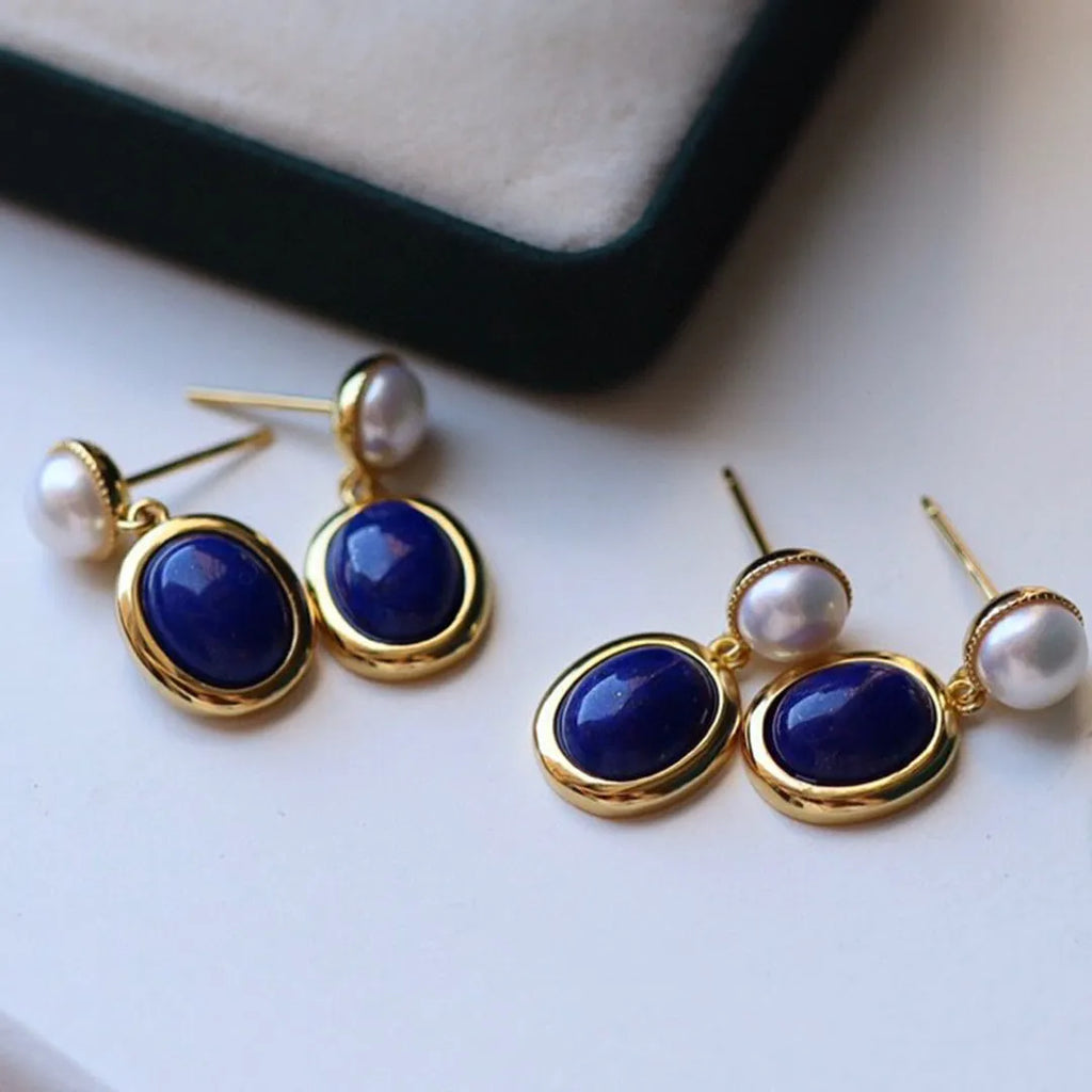 A pair of 925 sterling silver stud earrings with a deep blue lapis lazuli pearl and auspicious pattern details.