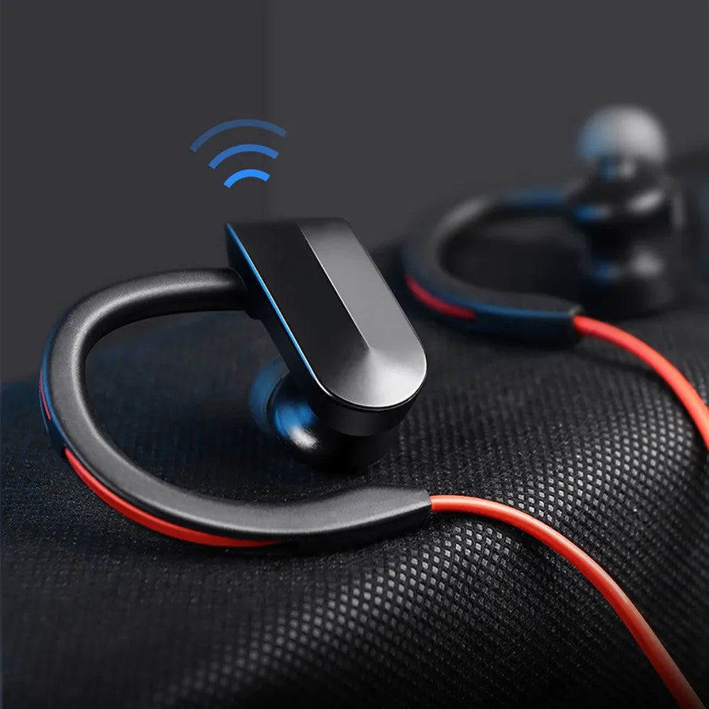 Black wireless neckband Bluetooth earphones with earbuds and a USB charging cable on a grey background.
