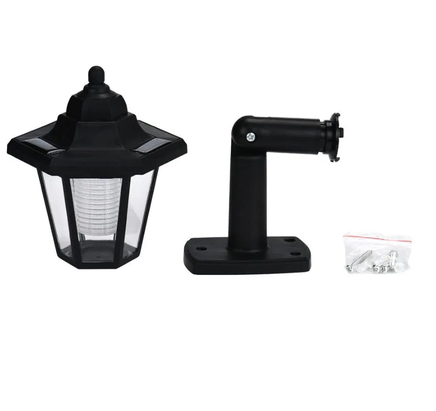 Black hexagonal solar-powered wall lamp for outdoor garden use, shown mounted on a fence