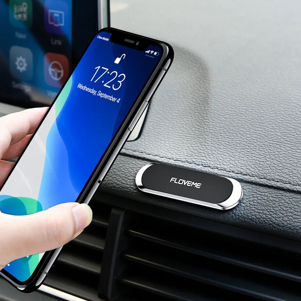 Black magnetic car phone holder mounted on windscreen with silver iron sheet for mobile phone attachment