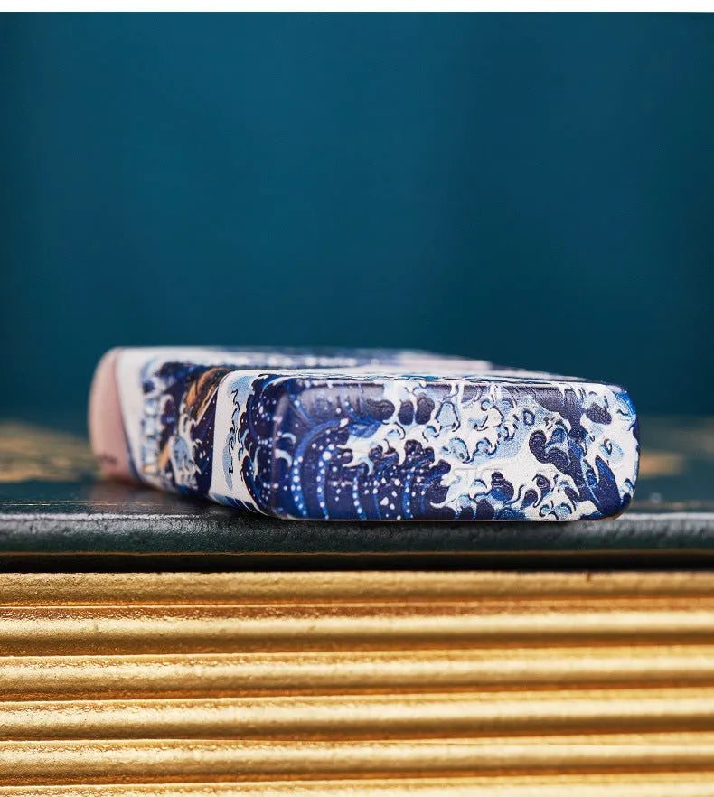 Coloured lacquer windproof lighter with Kanagawa surf design, steel inner liner, copper housing, 58 x 39 x 13mm.