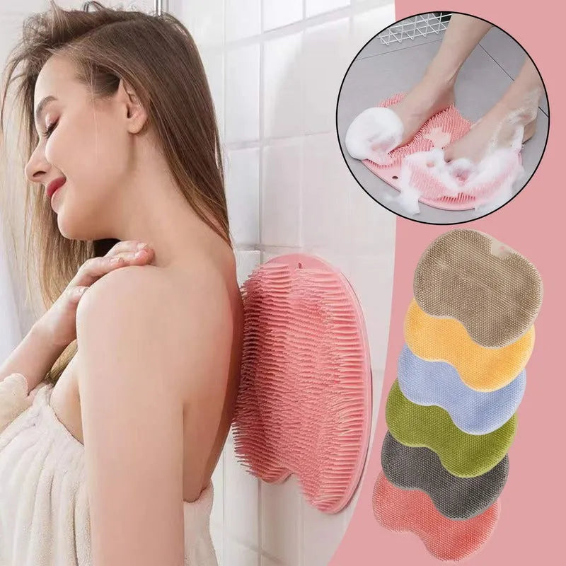 Orange silicone suction cup bath brush with bristles for back and foot massage on a bathroom floor.
