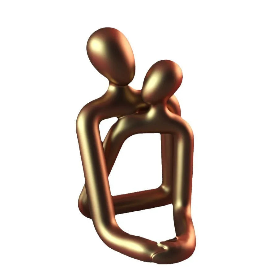 Modern heartwarming couple resin statue in milky white or gold colour on a wooden desk.