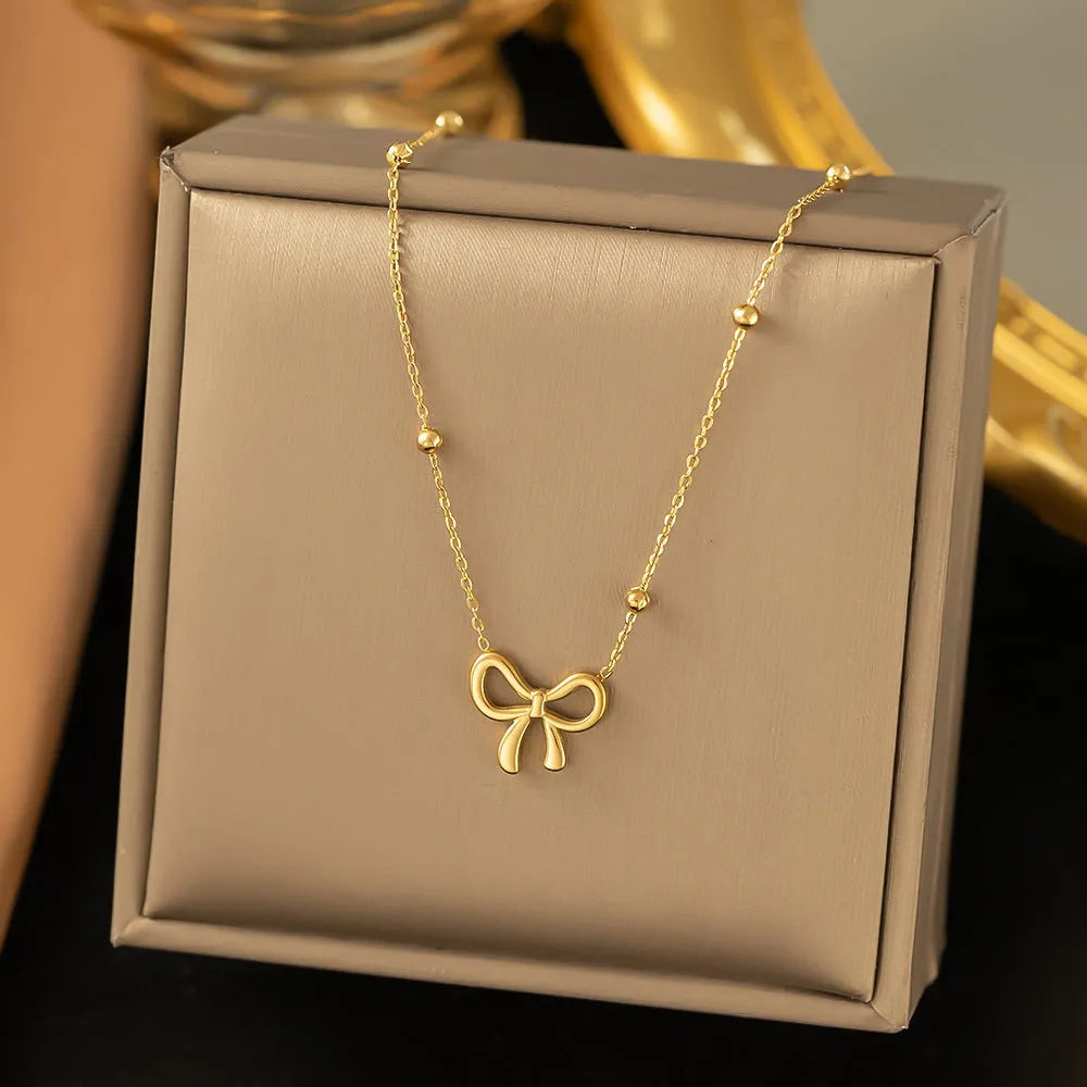 Gold electroplated titanium steel bow necklace with cross chain style on white background