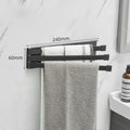 Black folding towel rack mounted on bathroom wall with towel hanging