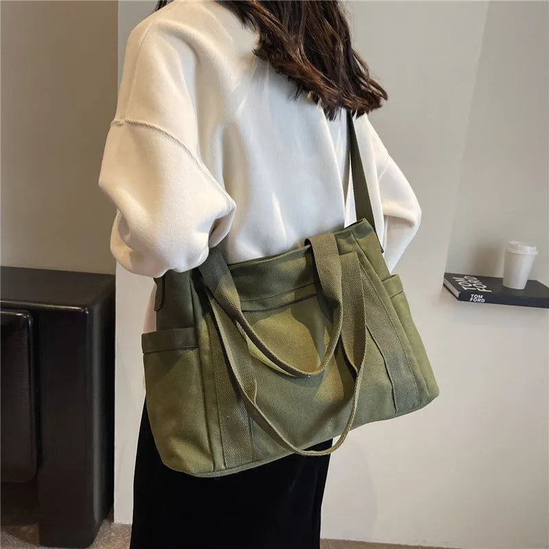 Women's solid colour canvas shoulder bag showing interior mobile phone compartment and exterior sandwich pocket