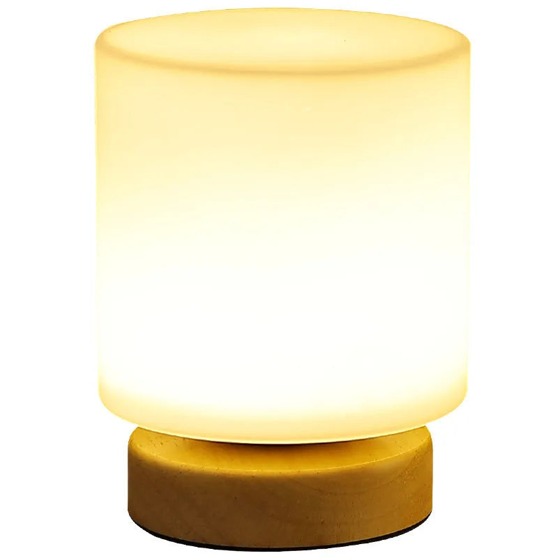 Nordic solid wood USB bedside lamp in a cube shape on a wooden table.