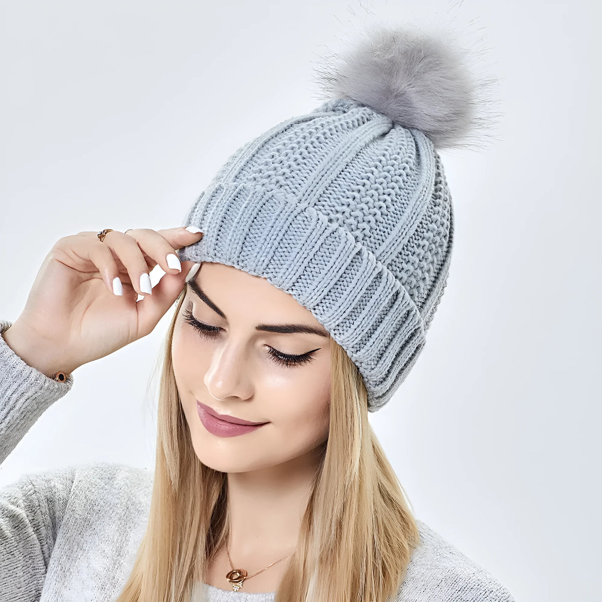 Women's black knit beanie with faux fur pom pom, showing satin lining and Paisley pattern inside.