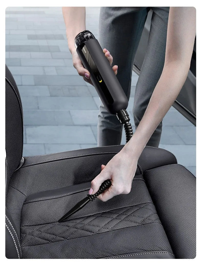 Black handheld wireless car vacuum cleaner with a blowing hose attachment on a desktop.