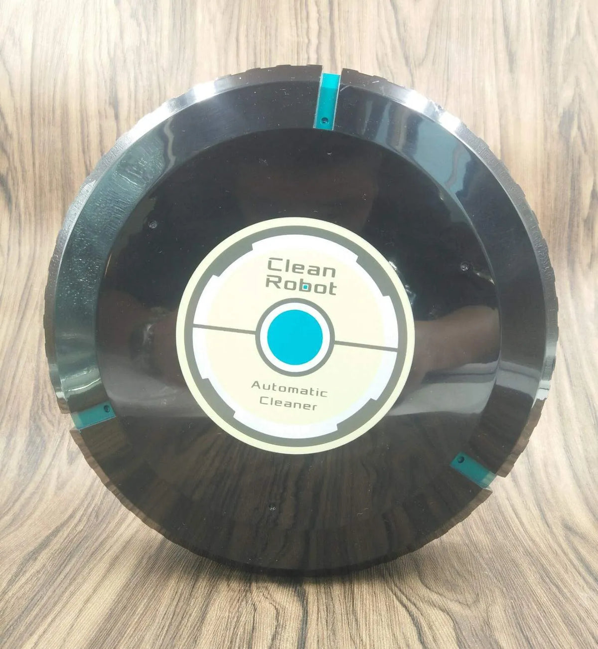 Black or white automatic sweeping robot on a wooden floor, showing compact square design.