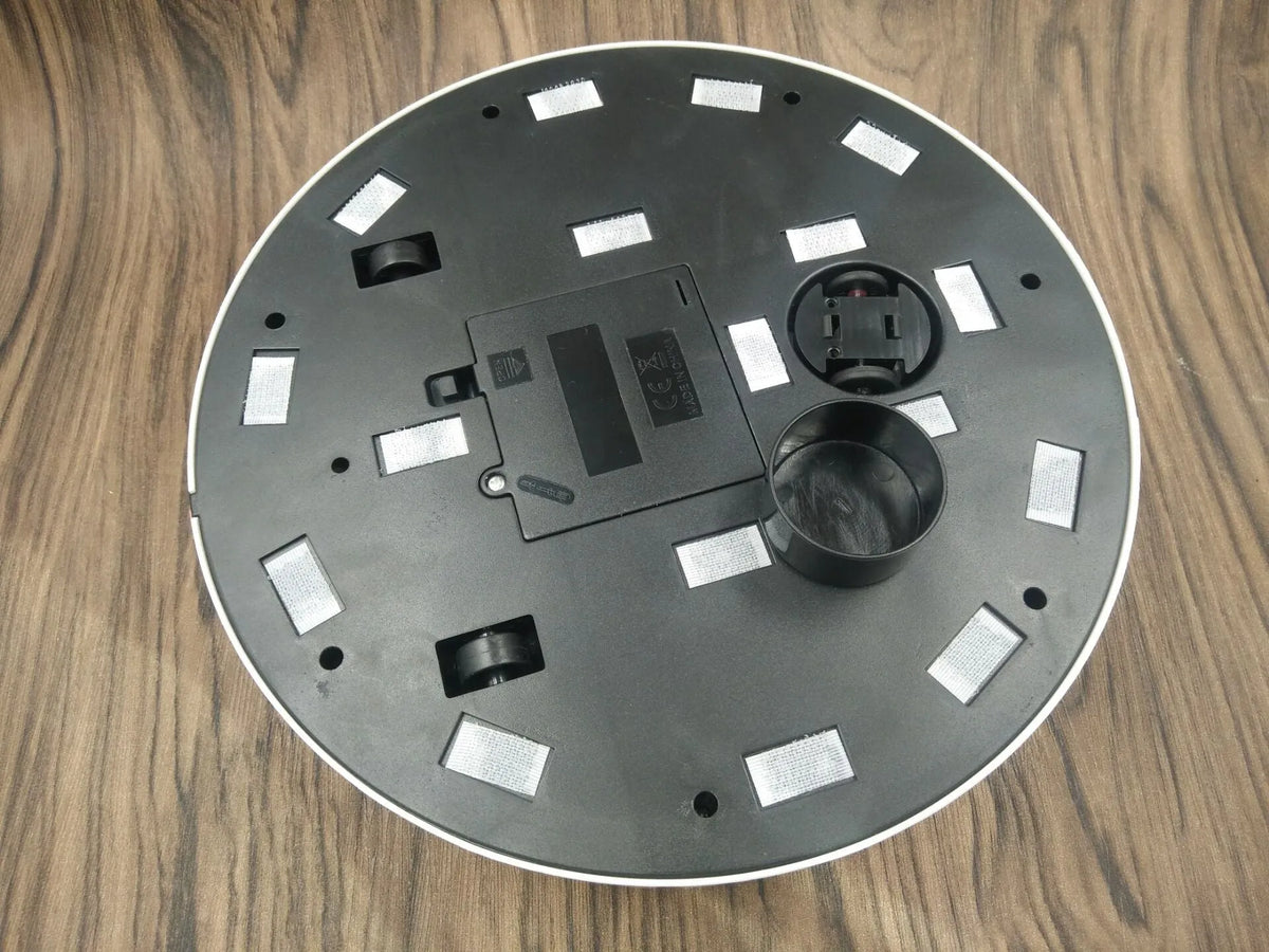 Black or white automatic sweeping robot on a wooden floor, showing compact square design.