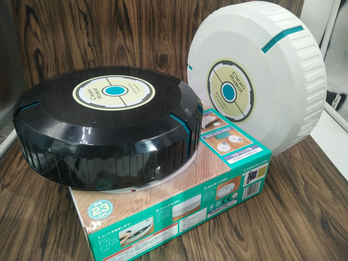 Black or white automatic sweeping robot on a wooden floor, showing compact square design.