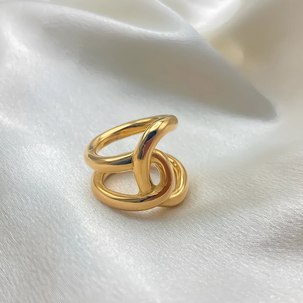 A gold-coloured geometric U-shaped ring with an adjustable opening and a knotted detail.