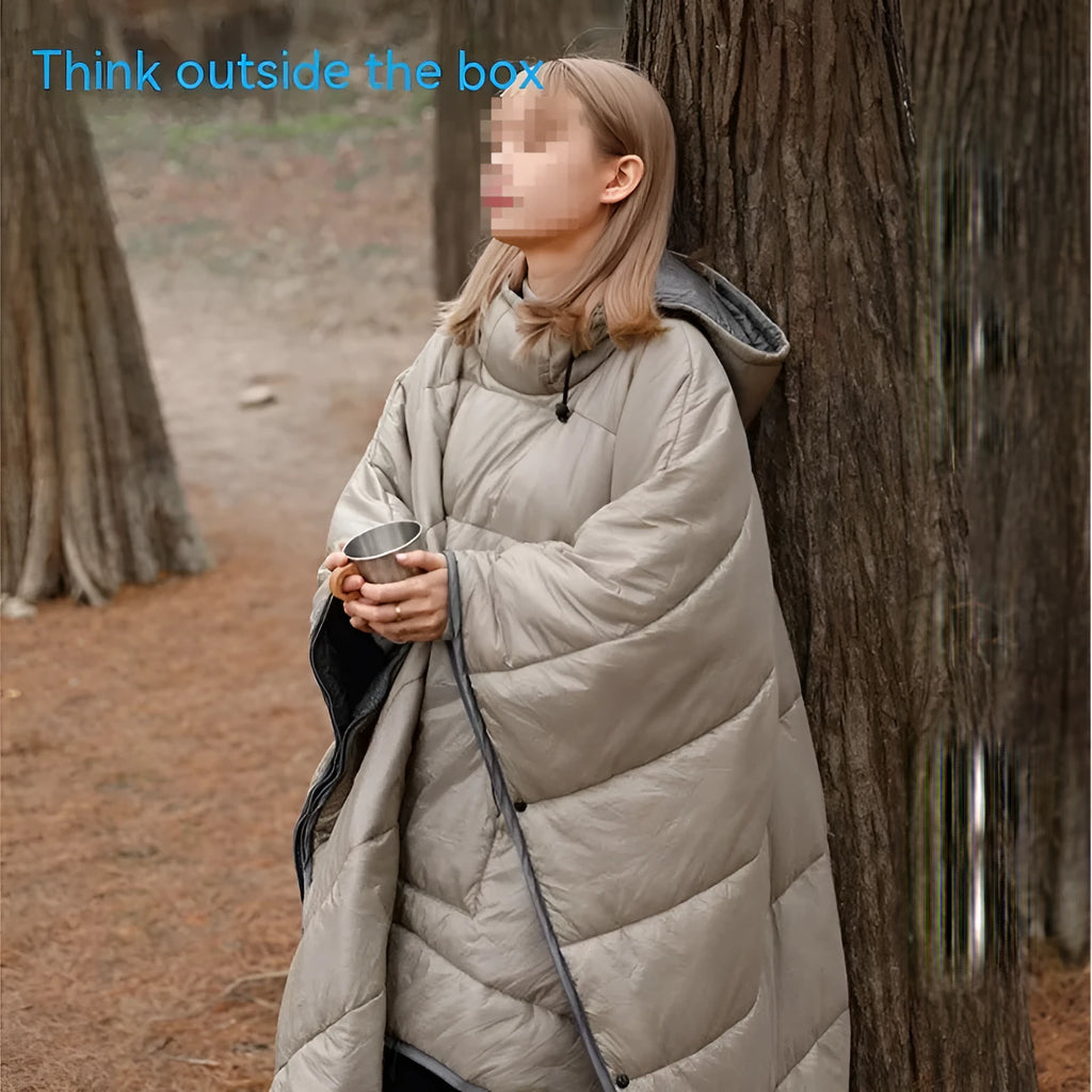 Adult wearing a grey outdoor cloak sleeping bag, showing its full 200x140cm size and hood.