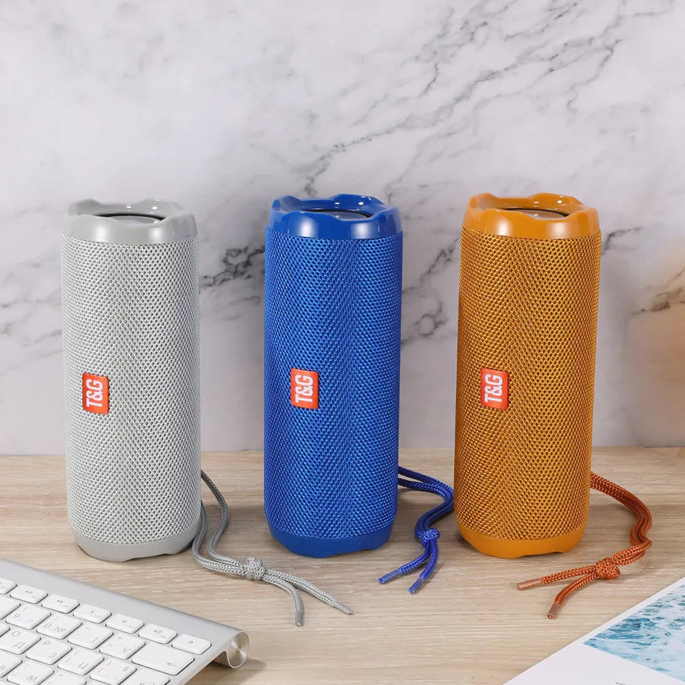Fabric-covered portable wireless Bluetooth speaker with a card holder, shown in multiple colour options.