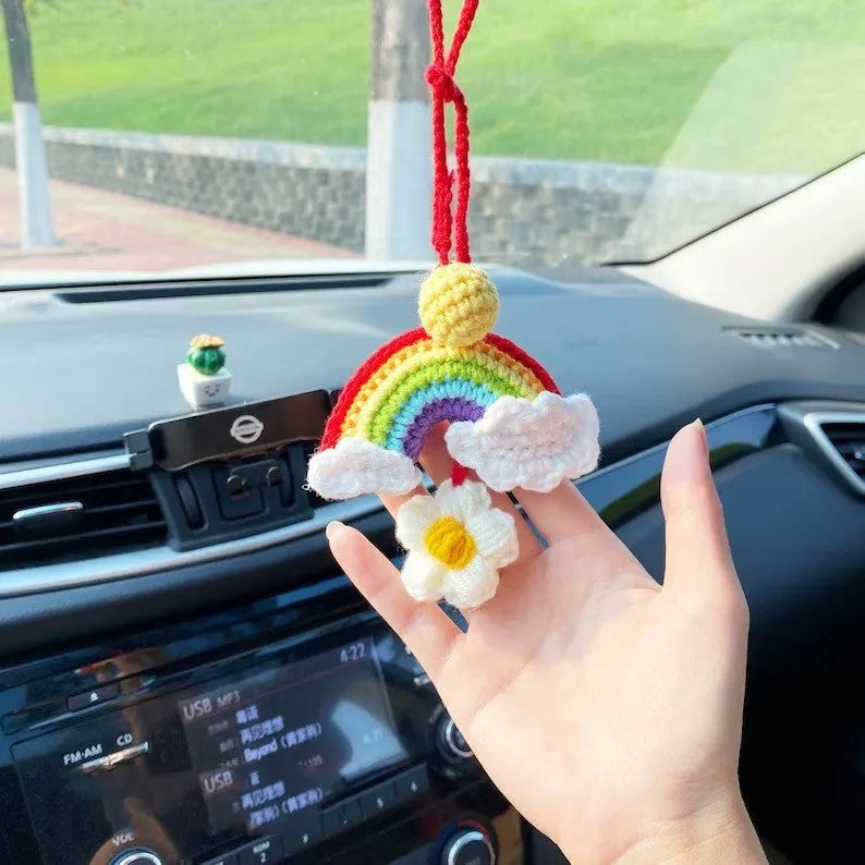 Handmade crocheted avocado-shaped car pendant with rainbow pattern, hanging.
