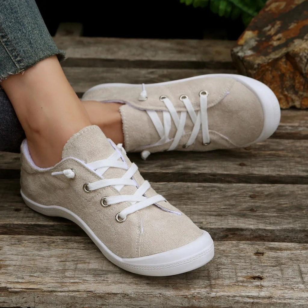 Women's creamy-white low-top fabric sneaker with rubber sole shown from side view