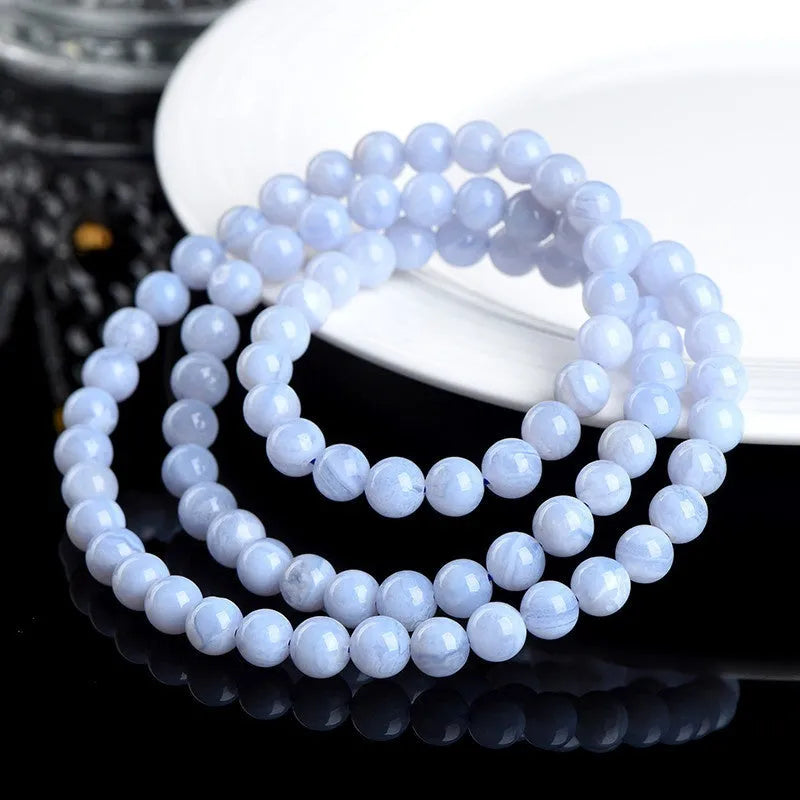Blue agate bead bracelet with striped pattern and ruyi design on a white background.