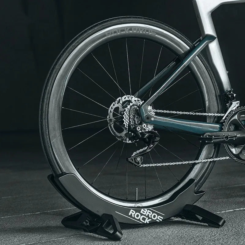 Black or green ABS plastic bicycle parking rack holder mounted on wall with road bike
