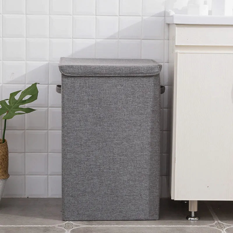 Foldable cotton linen storage basket in grey, shown in a modern room holding clothes and books.
