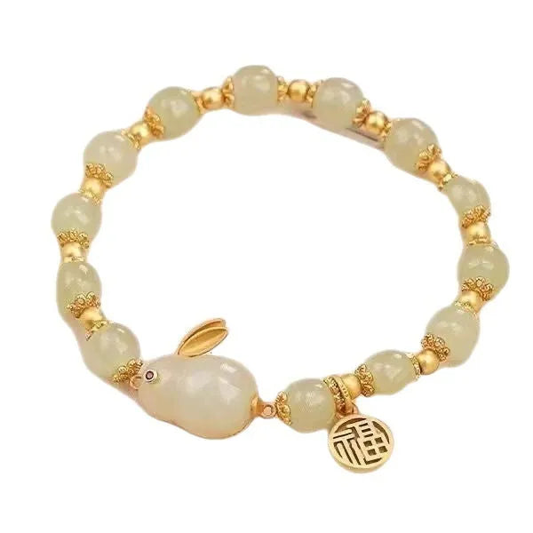 Close-up of a black women's bracelet with a green jade fu character charm and a metal hare pendant.
