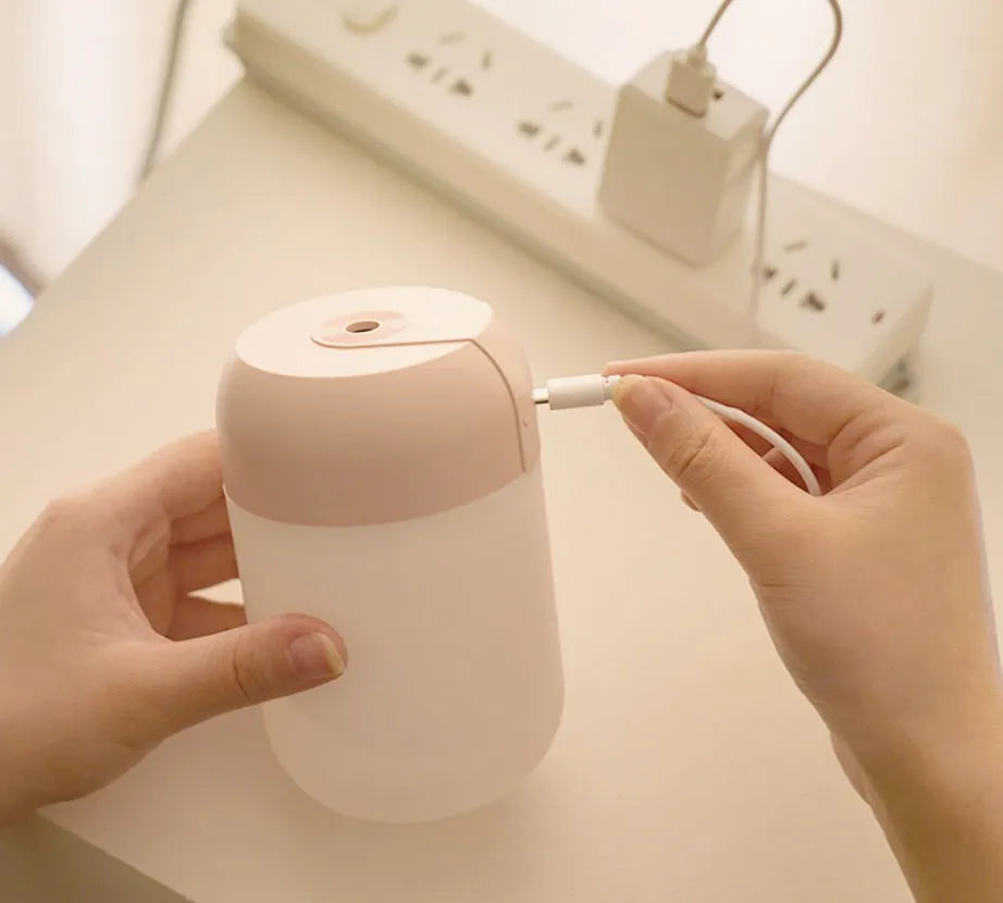 White cylindrical USB mini humidifier with charging cable on flat surface