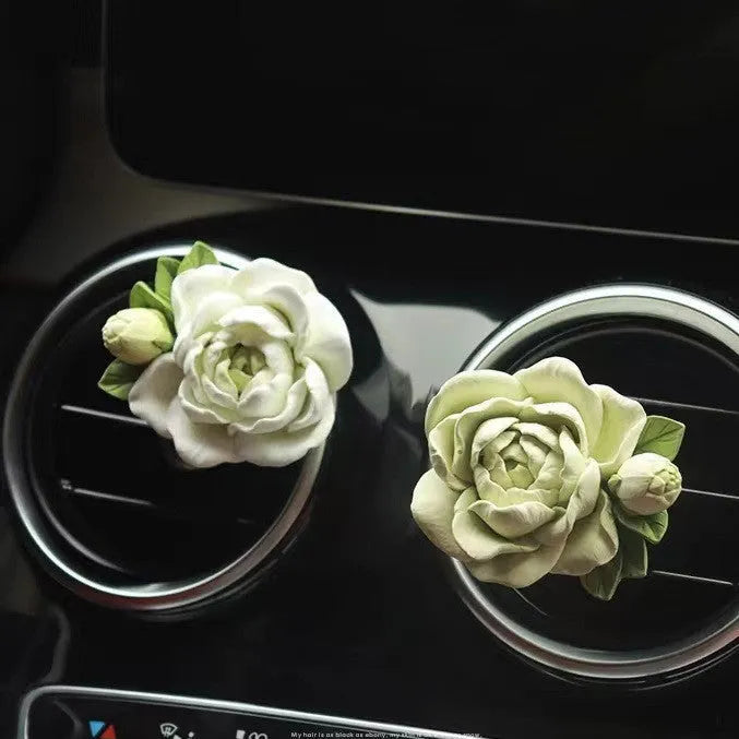 Jasmine car perfume solid air freshener in vent with gypsum base and essential oil bottle.