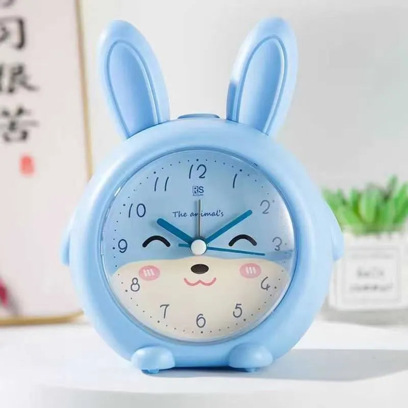 Pink and blue children's cartoon alarm clock with night light on a table