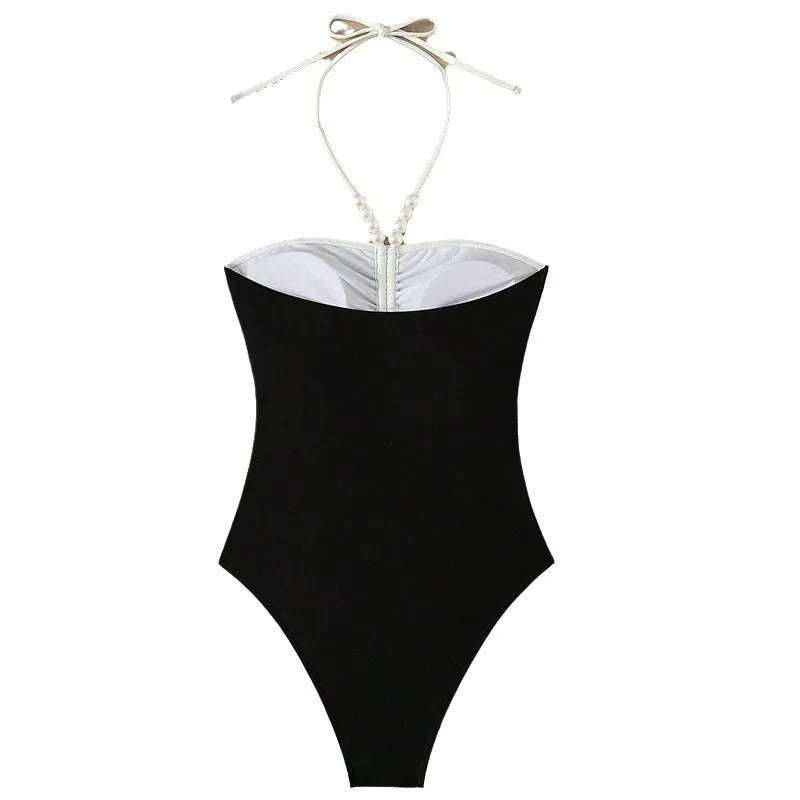 Black and white women's one-piece swimsuit with pearl-decorated spaghetti straps for a slimming fit.