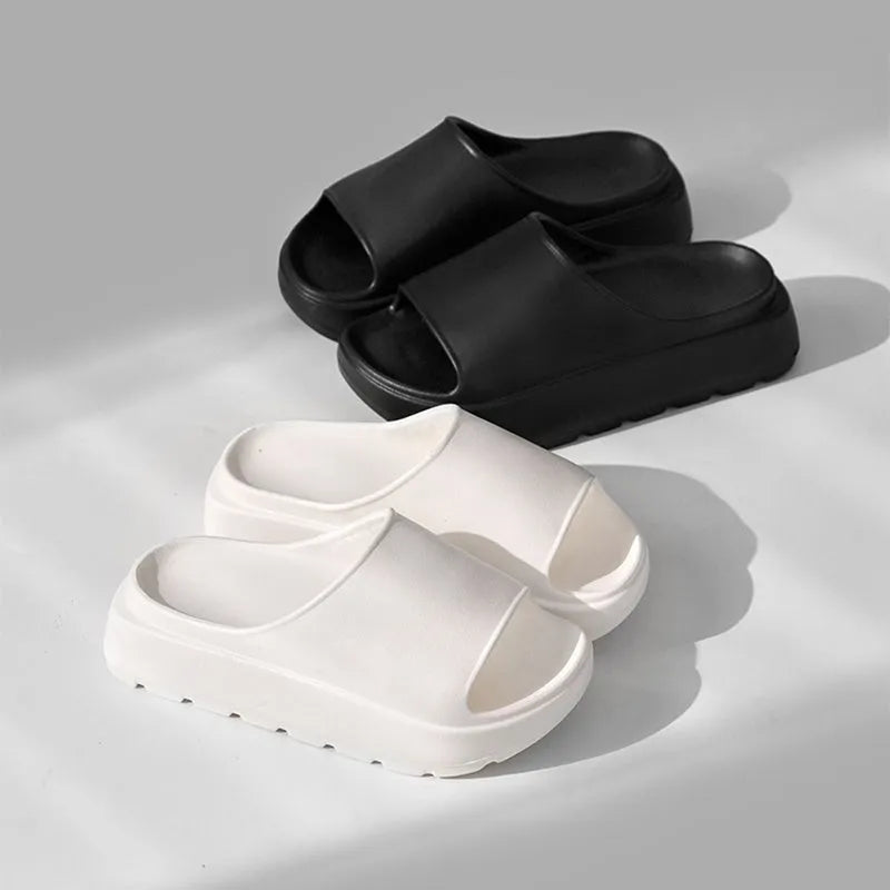 Women's thick-soled beige beach slippers with fish mouth design on a wooden deck.