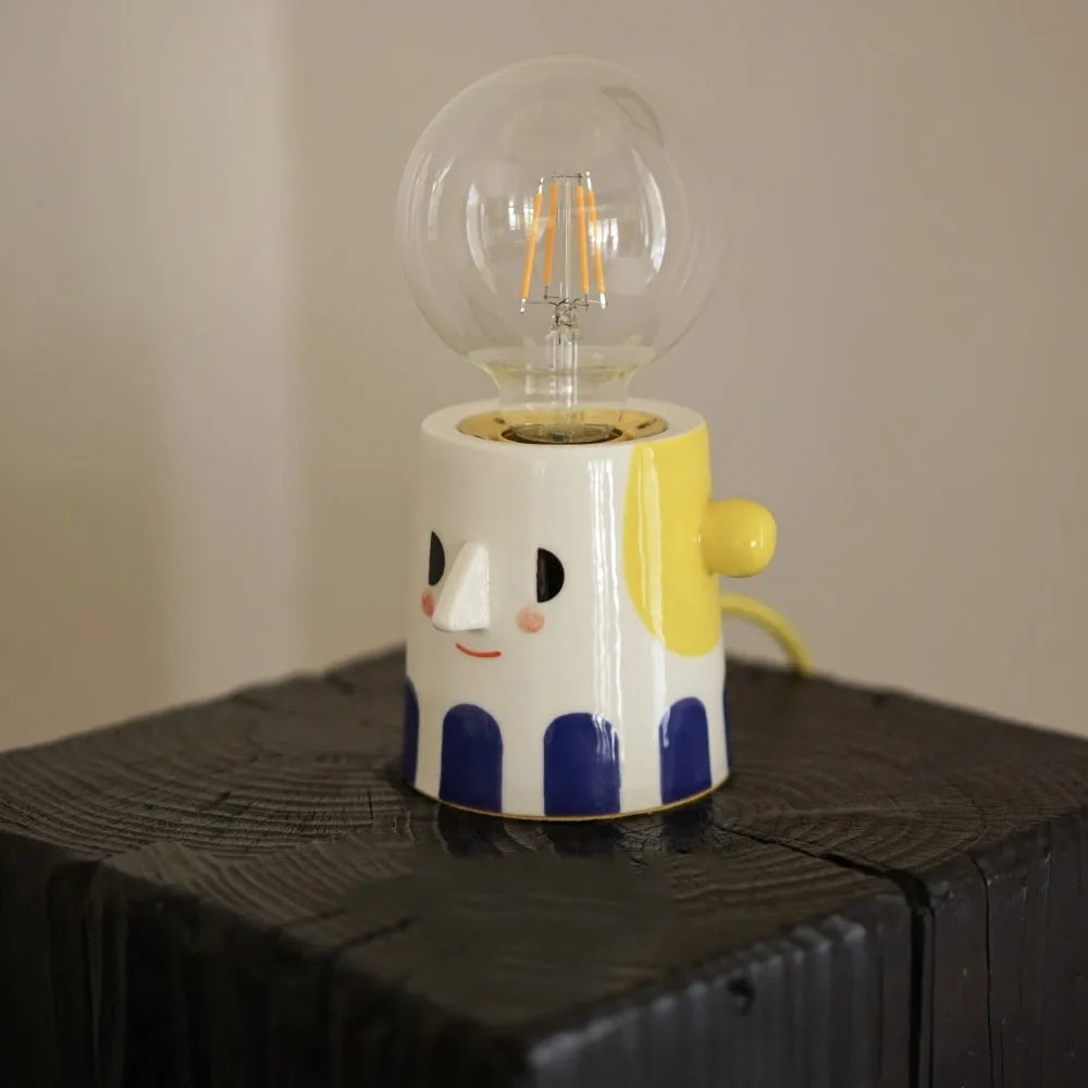 Handmade ceramic table lamp with white ball headlight design on wooden surface