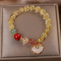 Close-up of a women's bracelet with a yellow citrine jade ruyi pendant on an adjustable alloy chain.
