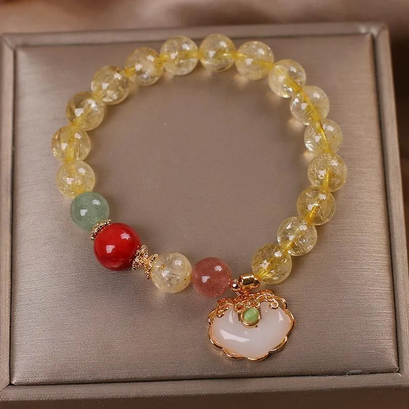Close-up of a women's bracelet with a yellow citrine jade ruyi pendant on an adjustable alloy chain.