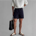 Cotton loose fit sports shorts in black, shown on a hanger.