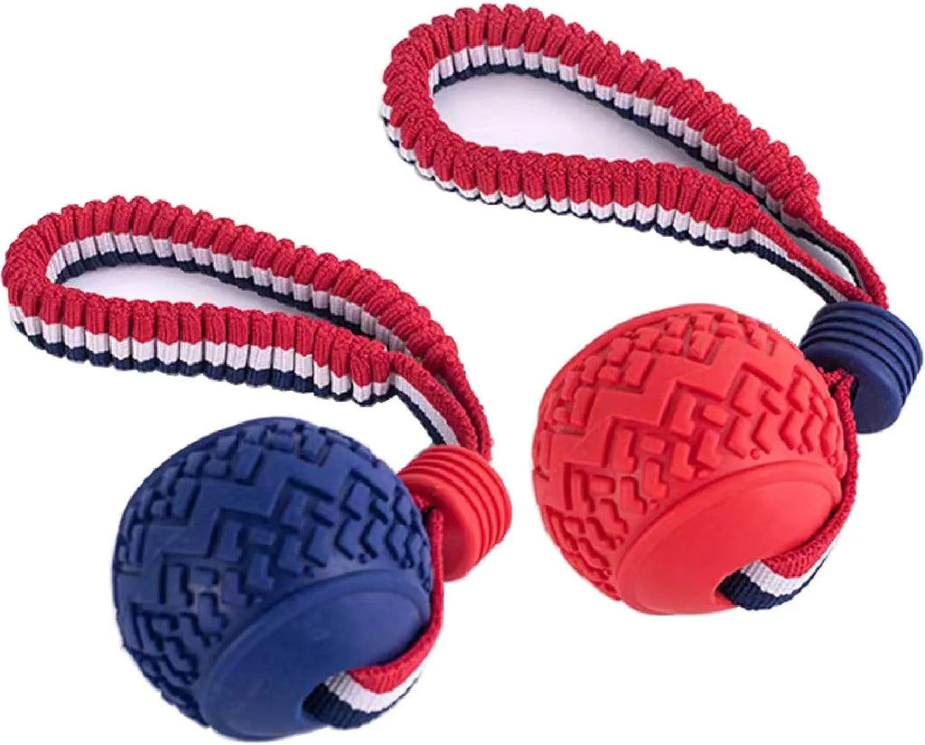 Blue natural rubber dog ball with integrated rope toy on grass, showing textured surface and scale.