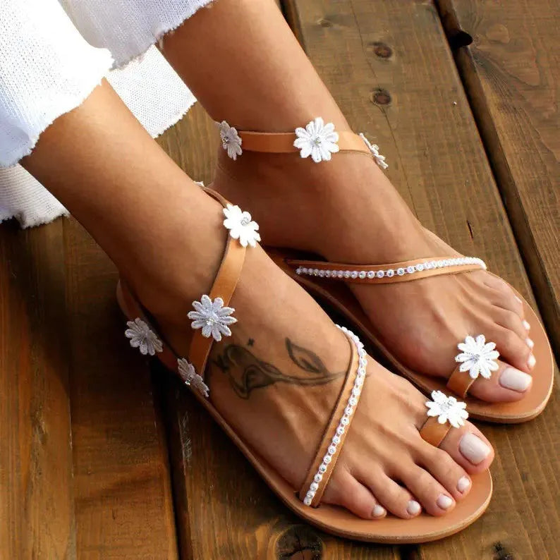 Brown flat casual sandals with a flower decoration and ethnic pattern on the upper.