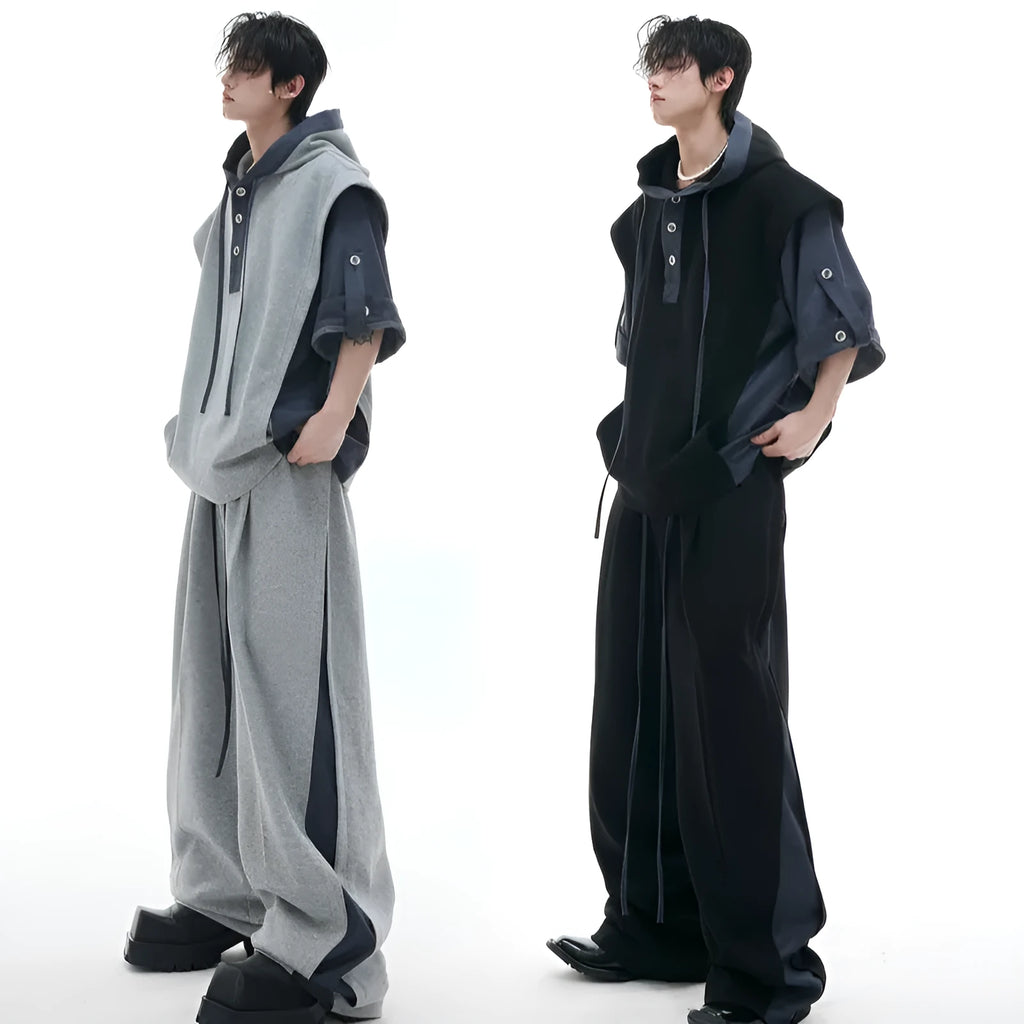 Man wearing a grey hooded short-sleeve sports jacket with textured stitching and black trousers.