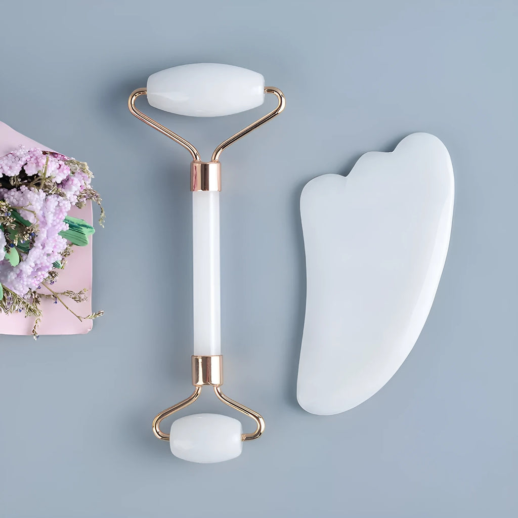 Natural white jade facial roller and Gua Sha scraper board set on a plain background.