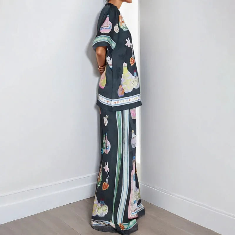 Black women's cardigan and pants set with cartoon animation pattern, laid flat.