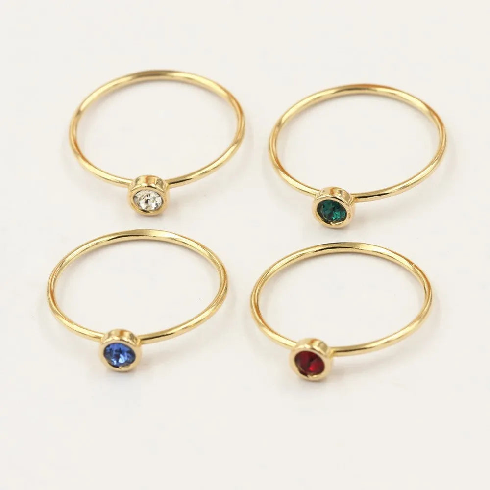 Copper knuckle ring with gold gild and coloured GF zircon stones on a finger.