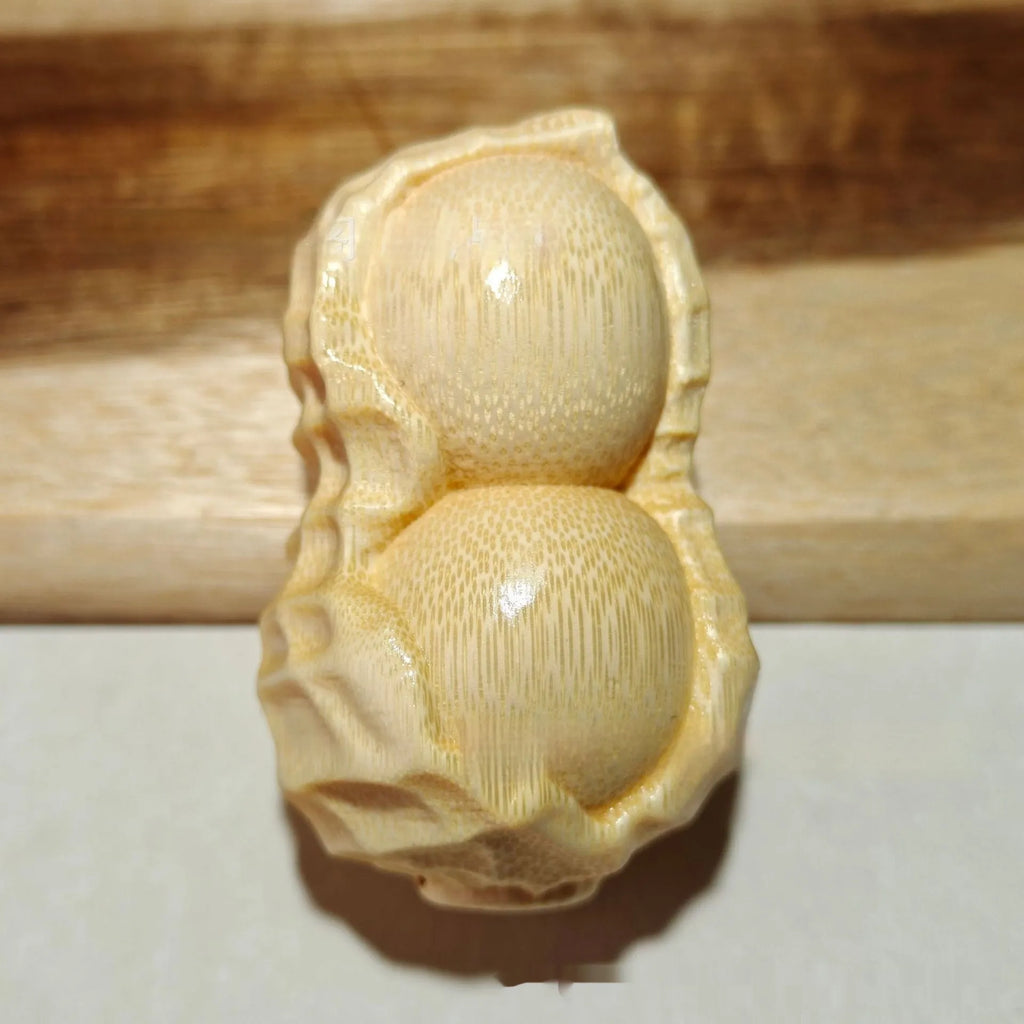 Solid natural bamboo carving peanut ornament on a neutral background