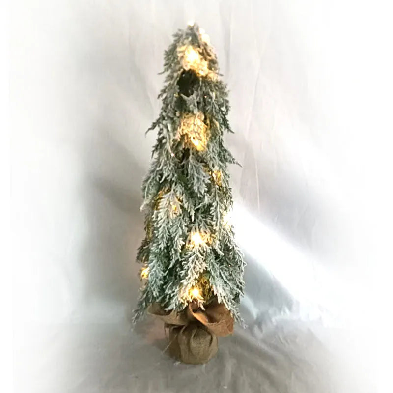 Small white artificial Christmas tree with built-in lights and snow sprayer decoration on desktop