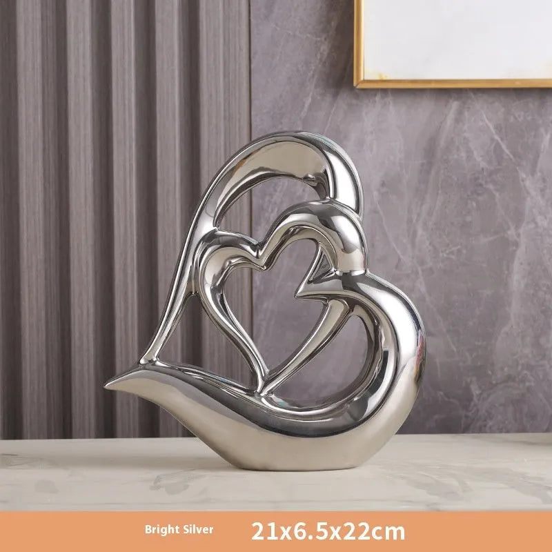 Modern geometric heart-shaped porcelain ornament in a metallic finish displayed on a cabinet.