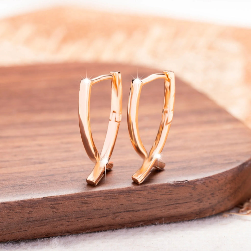 Rose gold cross shaped drop earrings with copper construction and light luxury finish