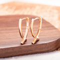 Rose gold cross shaped drop earrings with copper construction and light luxury finish