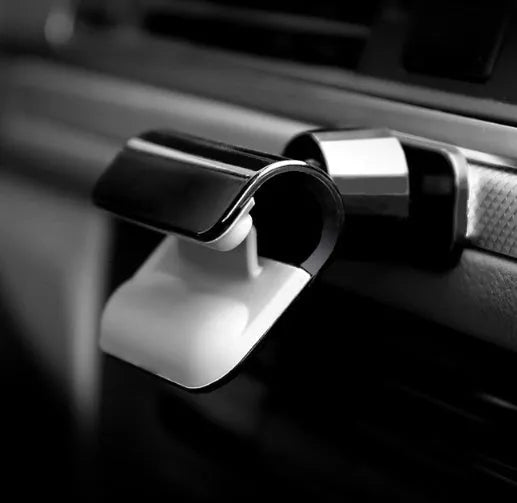 Black gravity car phone holder with 360-degree rotation on a car dashboard