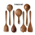 Set of seven wooden kitchen utensils including spoons and a spatula on a table.